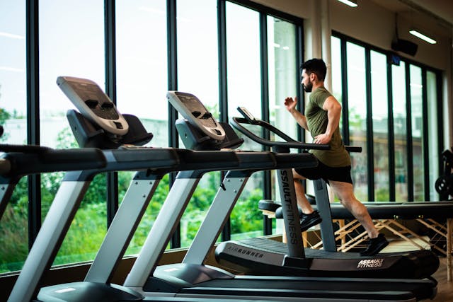 A man in a green t-shirt is running on the end treadmill in a line of them while looking out of the floor-to-ceiling windows in front of him. Image at PrimeOfficeSpace.co.uk.