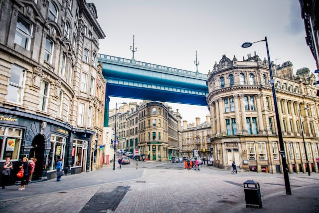 A daytime street view towards the intersection of three streets in old Grainger Town in Newcastle upon Tyne’s commercial centre. Multi-storey Georgian buildings flank the roads, and part of the blue-bottomed Tyne Bridge spans the intersection around the same level as the tops of the buildings. Image at LondonOfficeSpace.com.